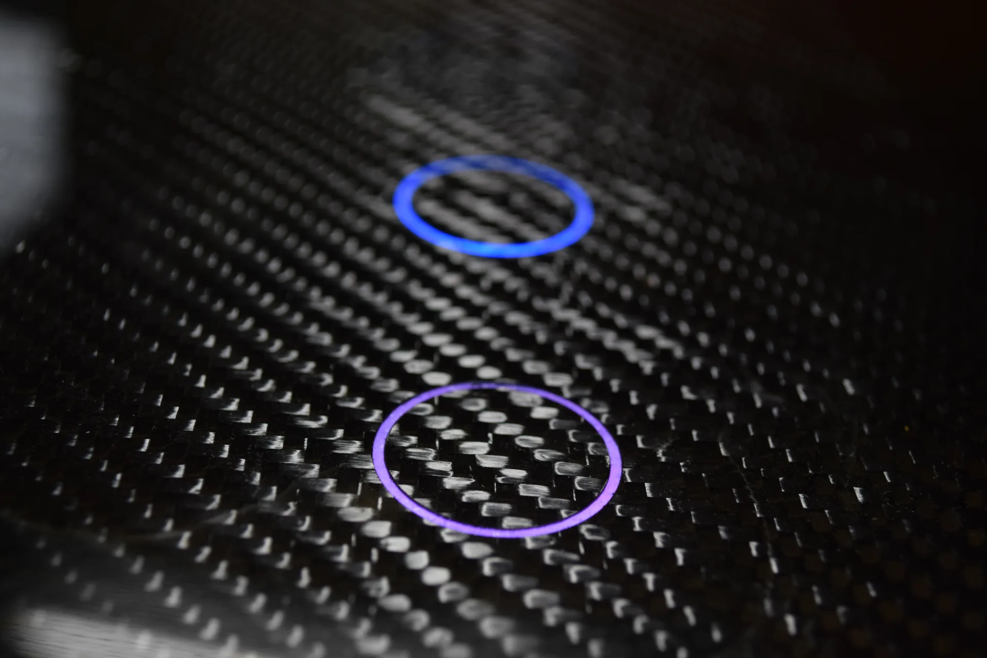 Close-up of dual sensing rings on carbon fiber weave